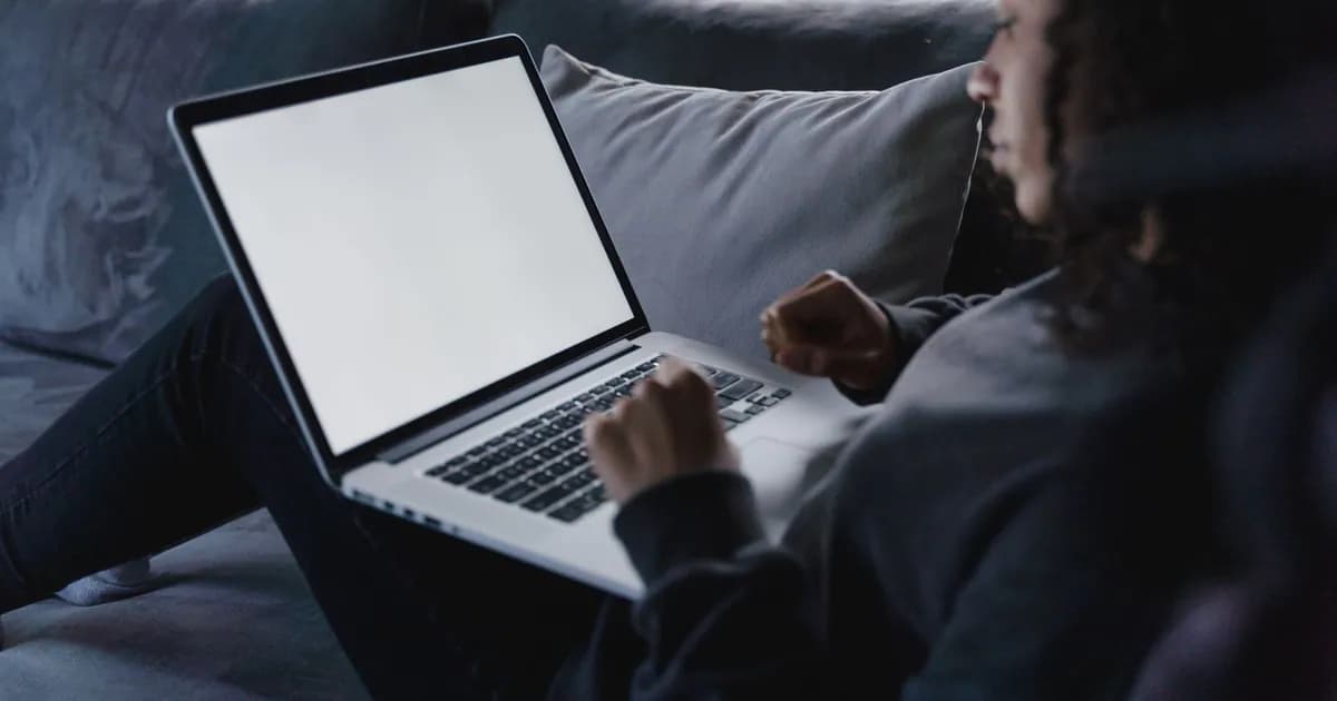 A young woman works on her laptop in a cozy living room, focusing on the blank screen