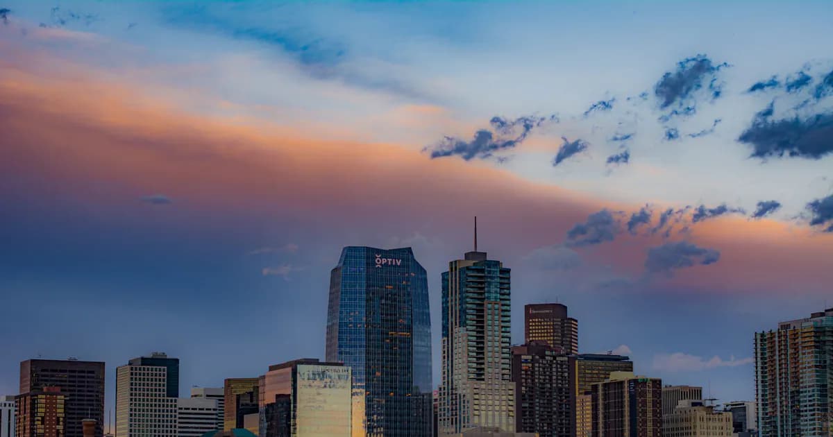 Stunning view of Denver's cityscape with skyscrapers under a colorful sunset sky