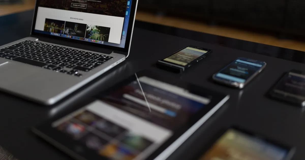Laptop, tablet and smartphones showing web pages on a dark desk