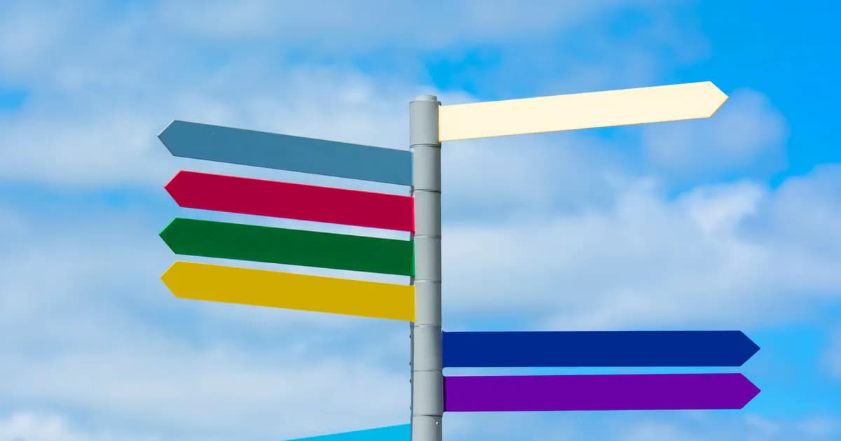 Multicolored directional signpost against a vibrant blue sky, offering guidance