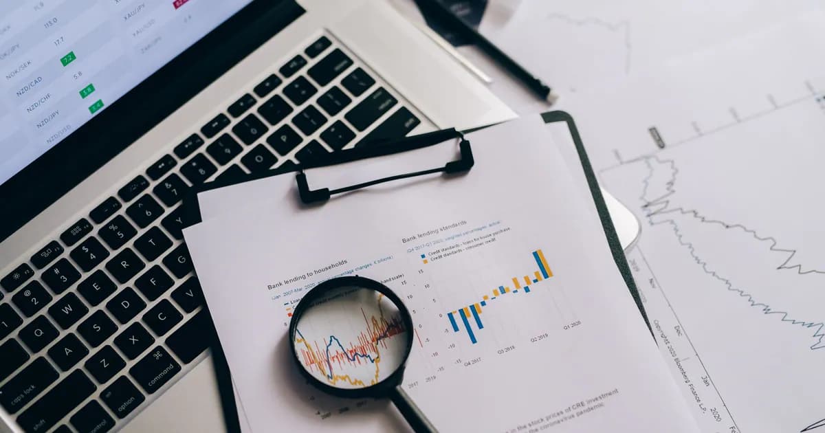 Overhead view of financial charts, laptop, and magnifying glass