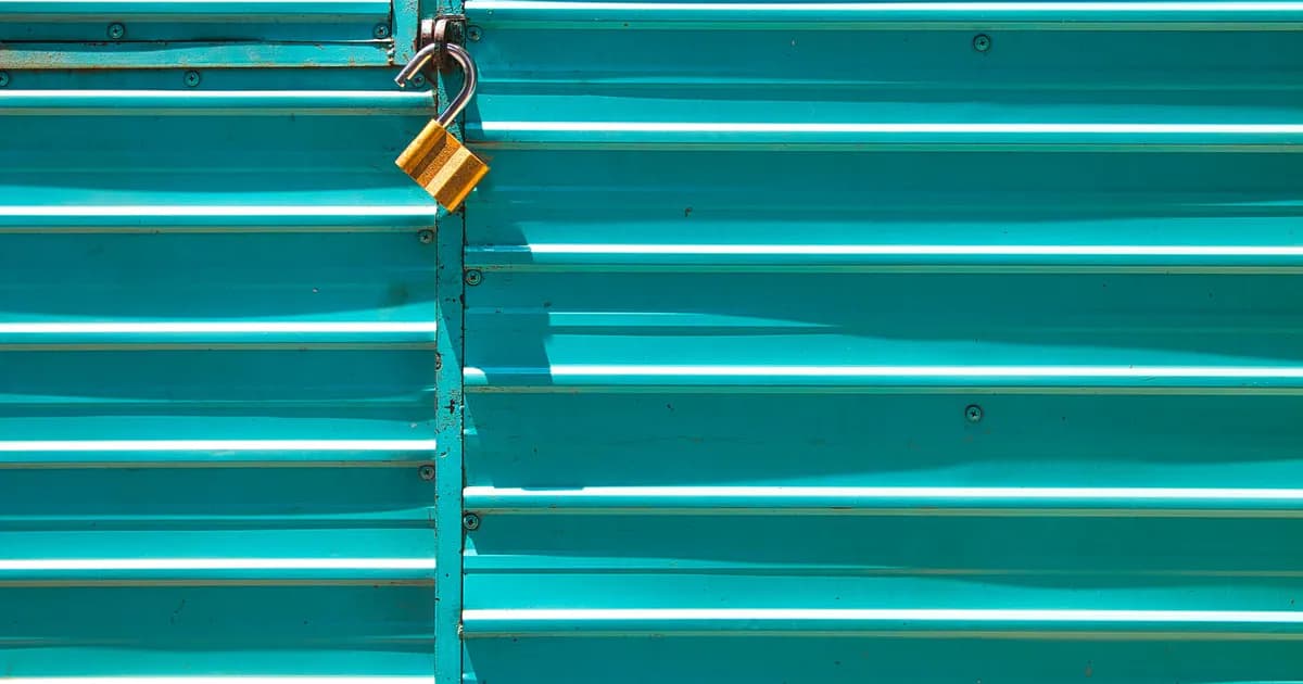 Close-up of a turquoise metal door with a golden padlock