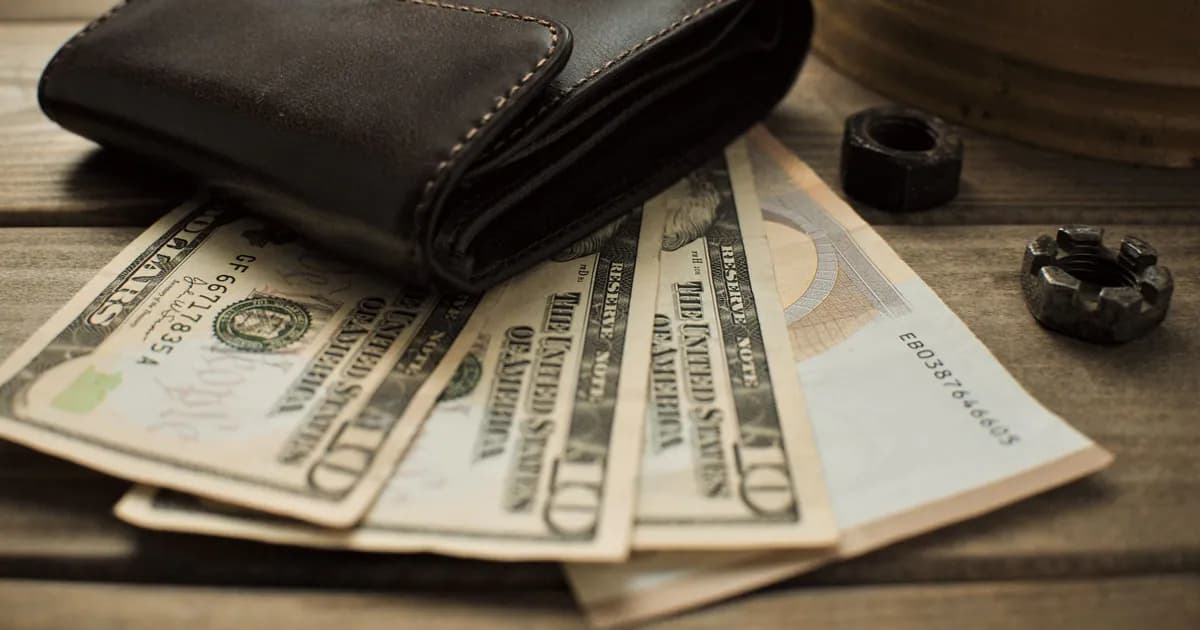 Close-up view of a leather wallet with US dollar bills on a wooden table