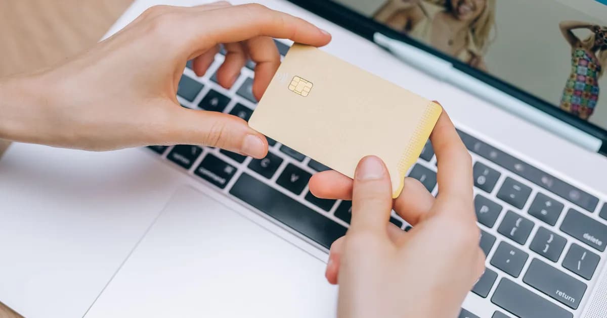 Close-up of hands holding credit card for online shopping on a laptop. Perfect for e-commerce and finance visuals