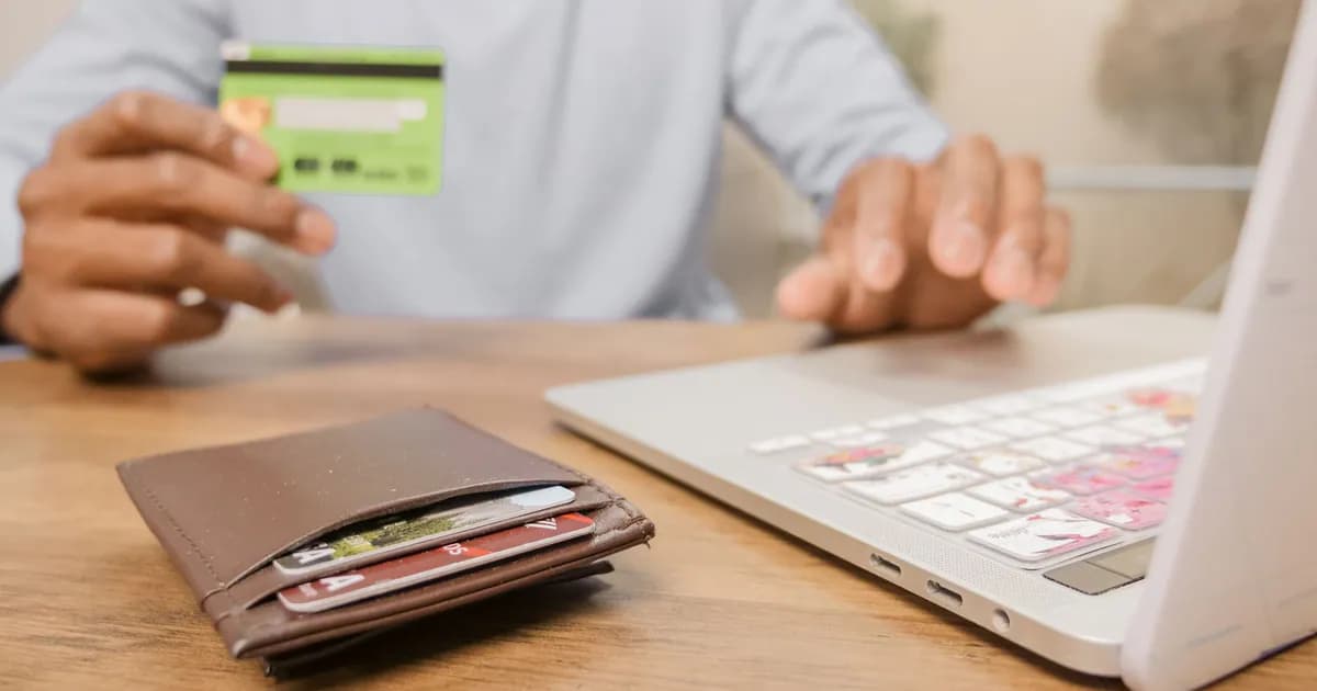 Close-up of hands with a bank card and laptop for online shopping. Perfect for illustrating e-commerce concepts