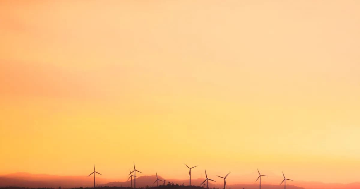 Silhouette of wind turbines at sunset, promoting sustainable energy
