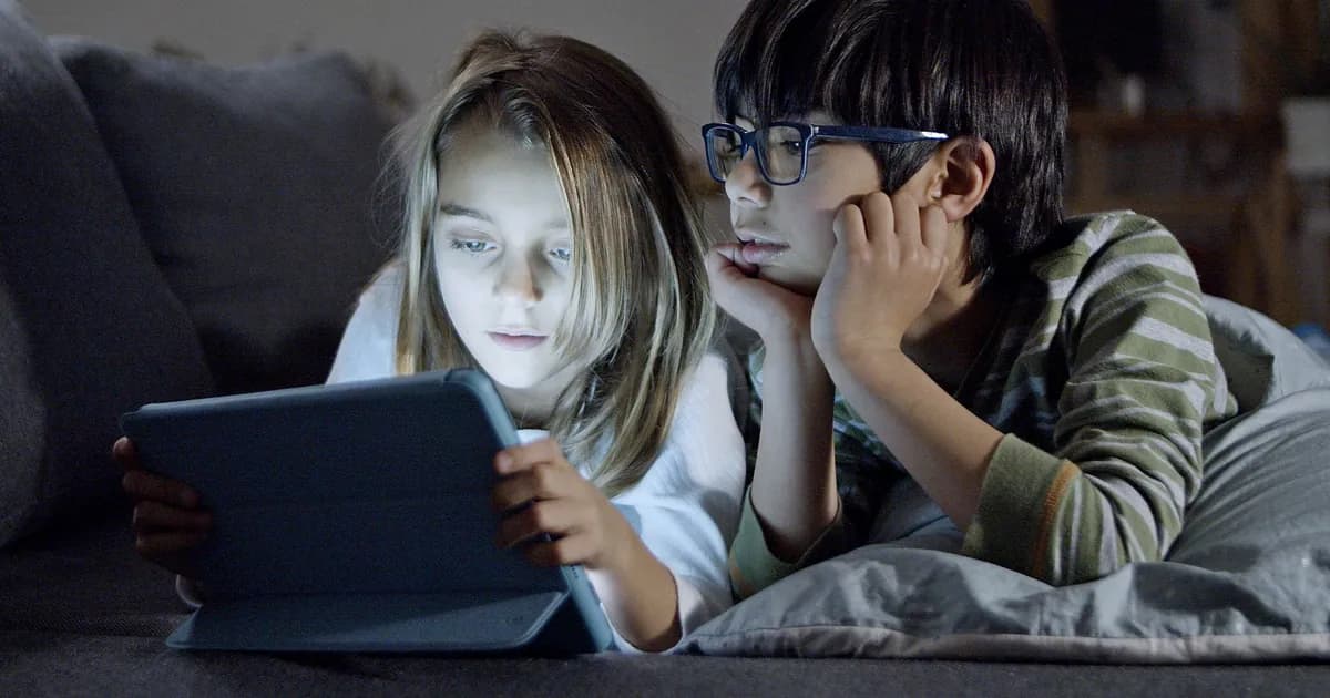 Two children using a tablet in a cozy home setting, engaging in screen time