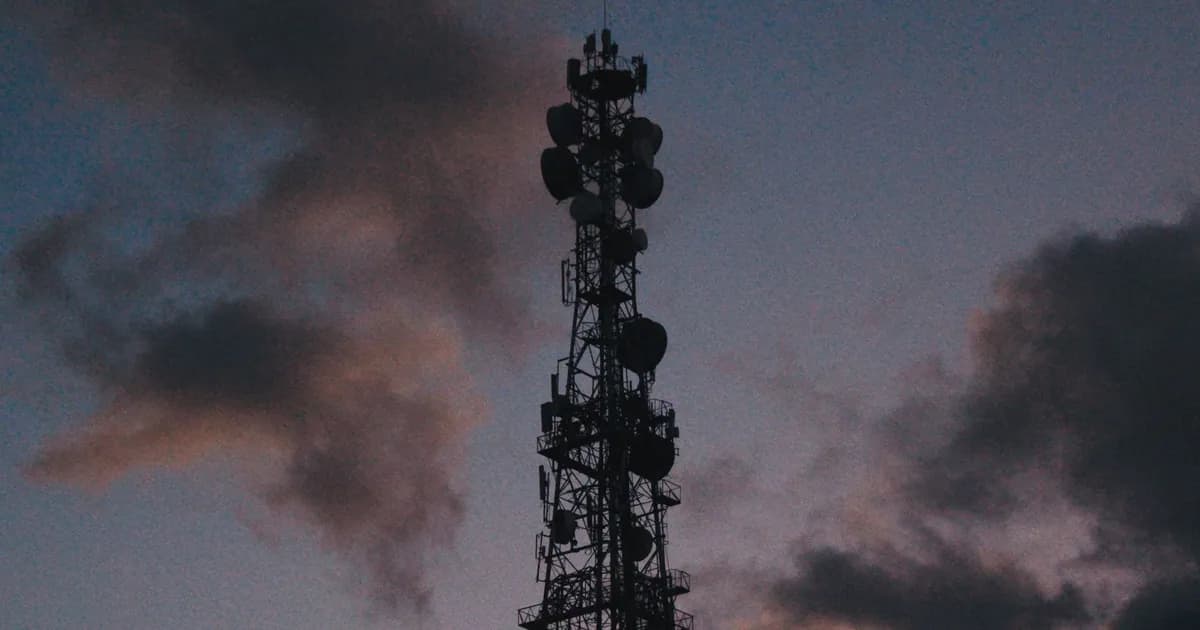 Silhouette of a telecommunications tower against a vibrant twilight sky with clouds