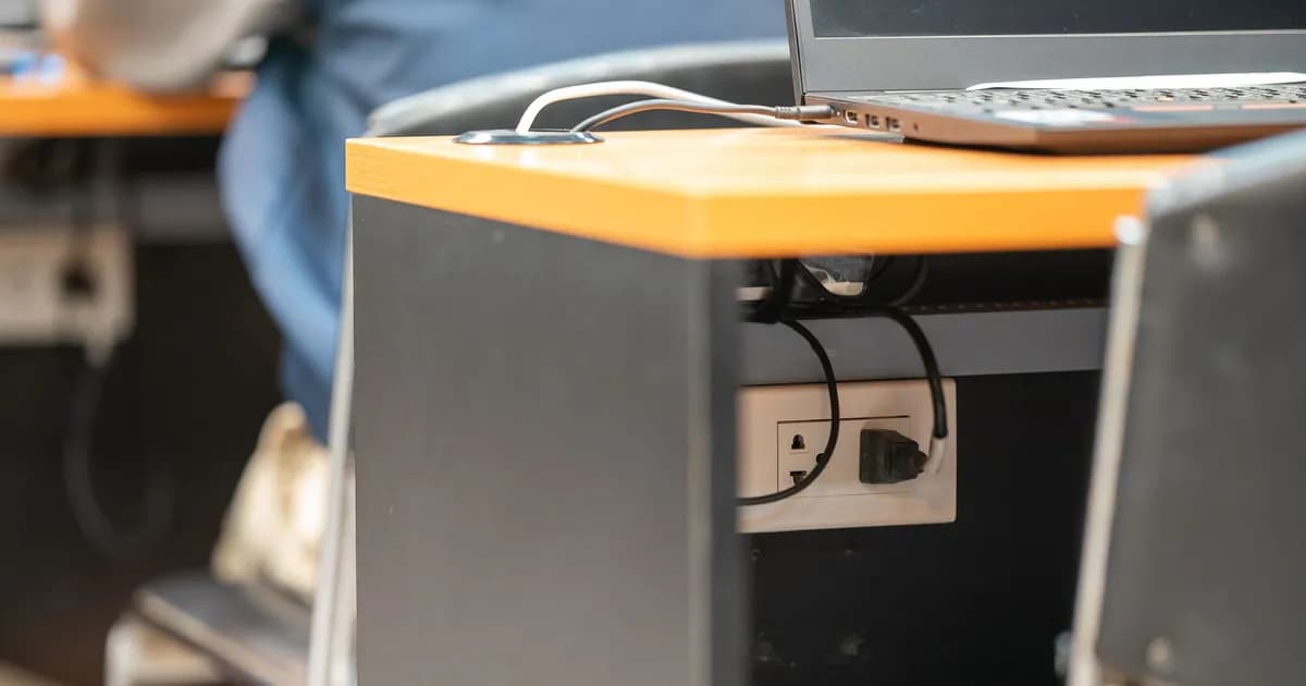 A clean office workspace featuring a desk, laptop, and hidden power cord management