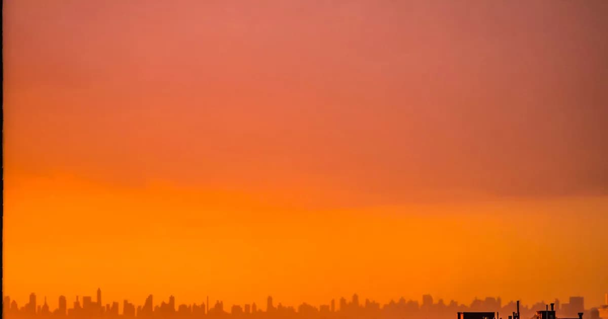 Capture the beauty of an urban skyline at sunset with warm orange hues and silhouetted buildings